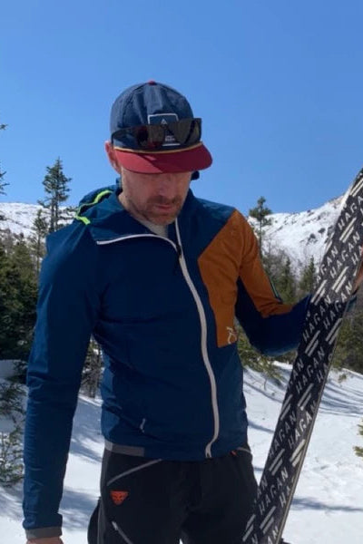 Person holding skis in a snowy mountain setting
