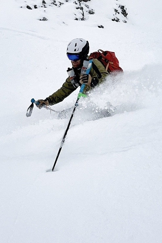 Person skiing down a snowy mountain with rocky outcrops