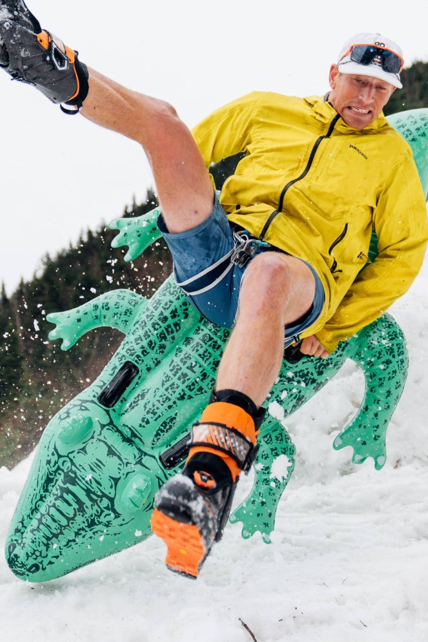 A skier riding an inflatable crocodile pool toy.