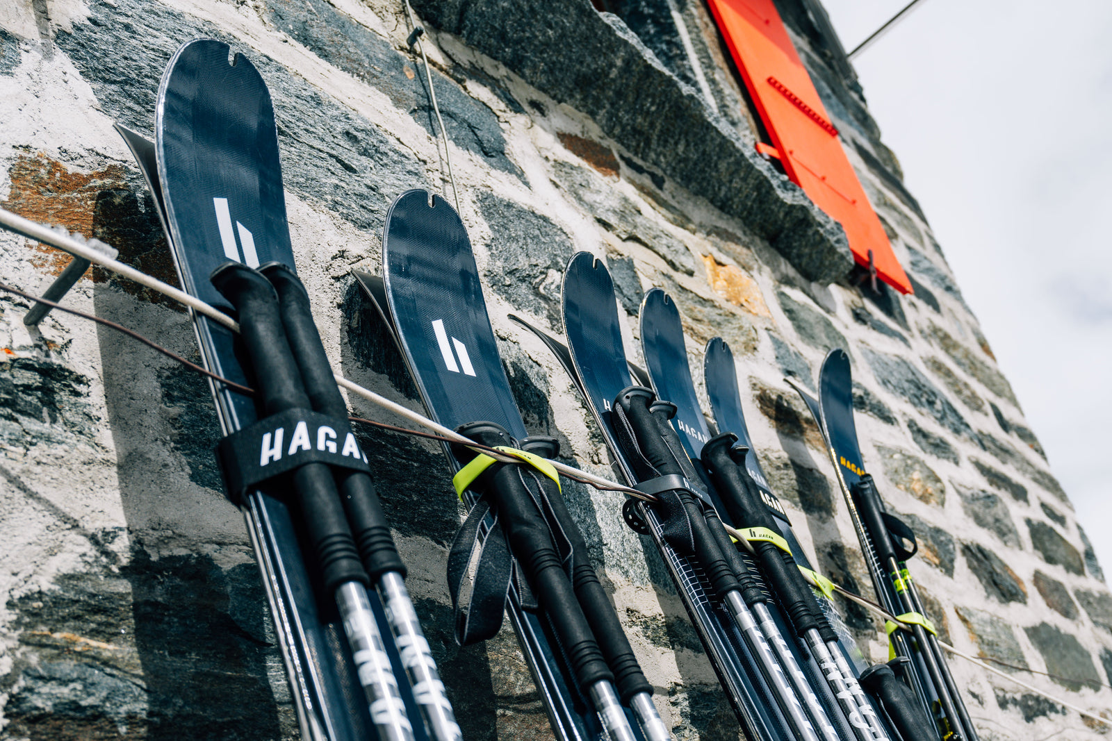 HAGAN Ultra skis lie against a stone wall.