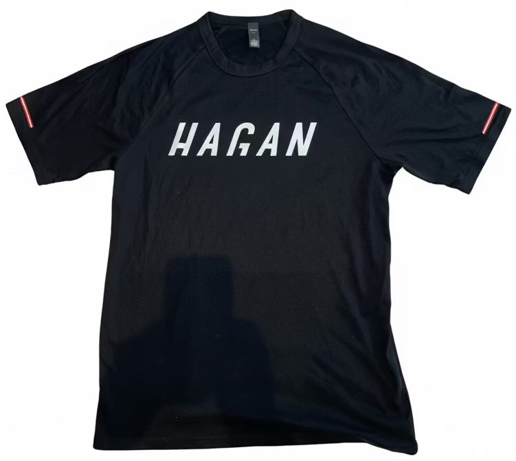 Black t-shirt with 'HAGAN' printed on it against a white background